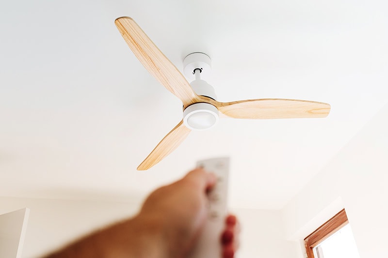 How to Choose the Right Ceiling Fan for Your Space. A person turning on a ceiling fan.
